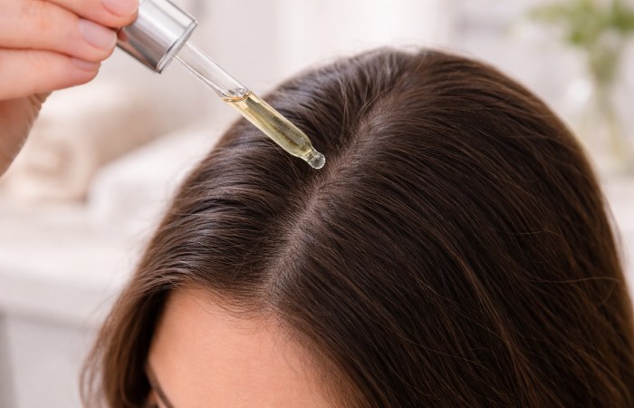 Applying hair growth serum directly to scalp using dropper